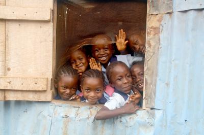 Escolares sonriendo tras una ventana en una escuela de hojalata